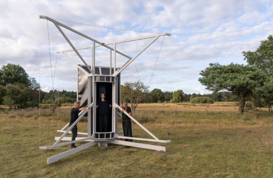 **ALT-Text:**<br />
Radioantenne mit integrierter Camera Obscura als Kunstinstallation auf einer Wiese, daneben zwei Personen.